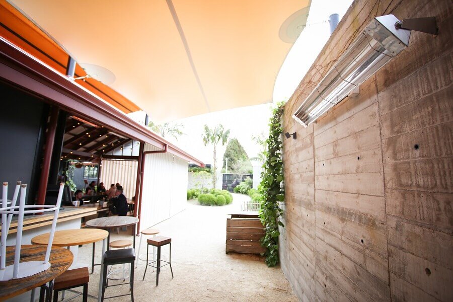 Kelray wall-mounted infrared heater installed at a modern café restaurant outdoor space — blending industrial style with functional heating for hospitality environments