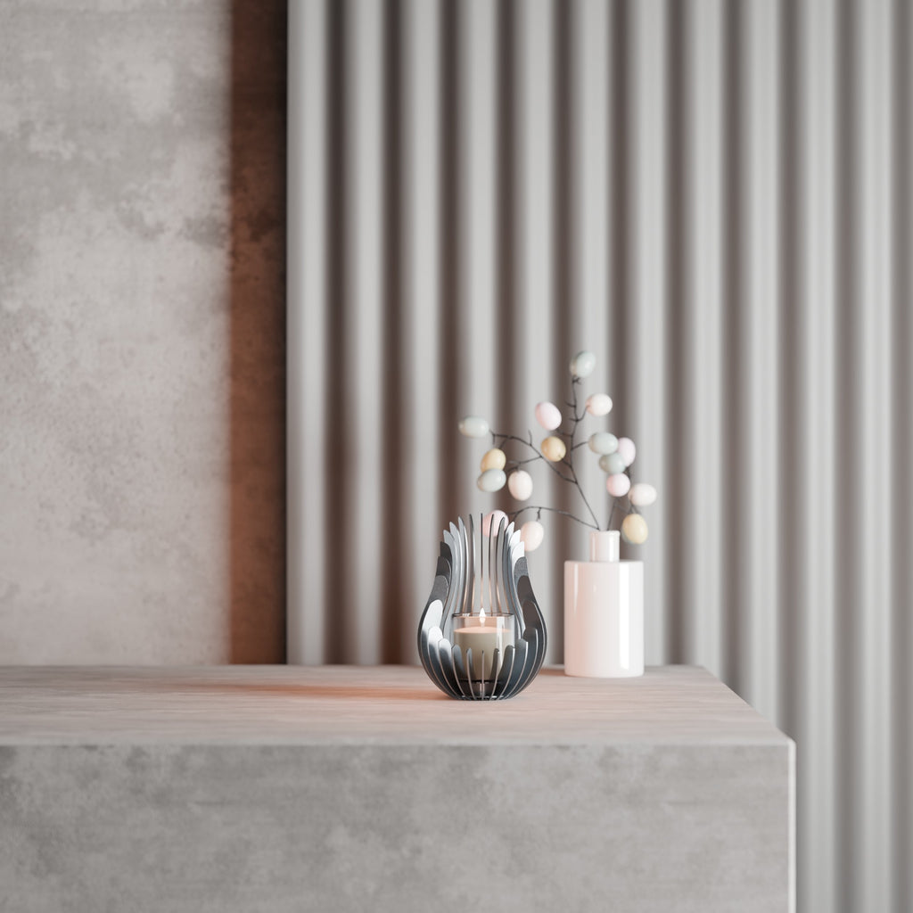 Kelray stainless steel candle holder with lit candle styled on a minimalist concrete pedestal next to a sculptural ceramic vase and pastel floral arrangement.