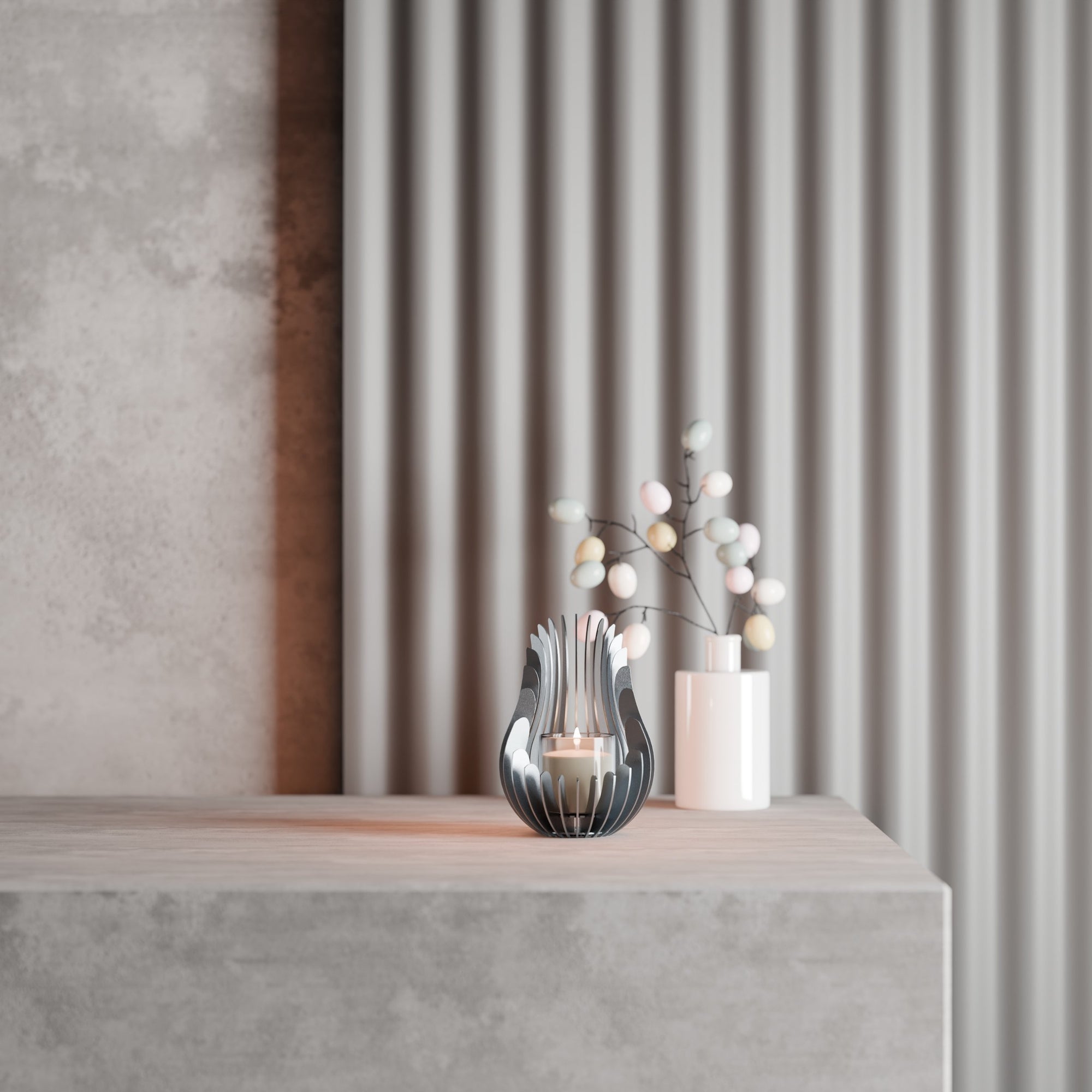 Kelray stainless steel candle holder with lit candle styled on a minimalist concrete pedestal next to a sculptural ceramic vase and pastel floral arrangement.
