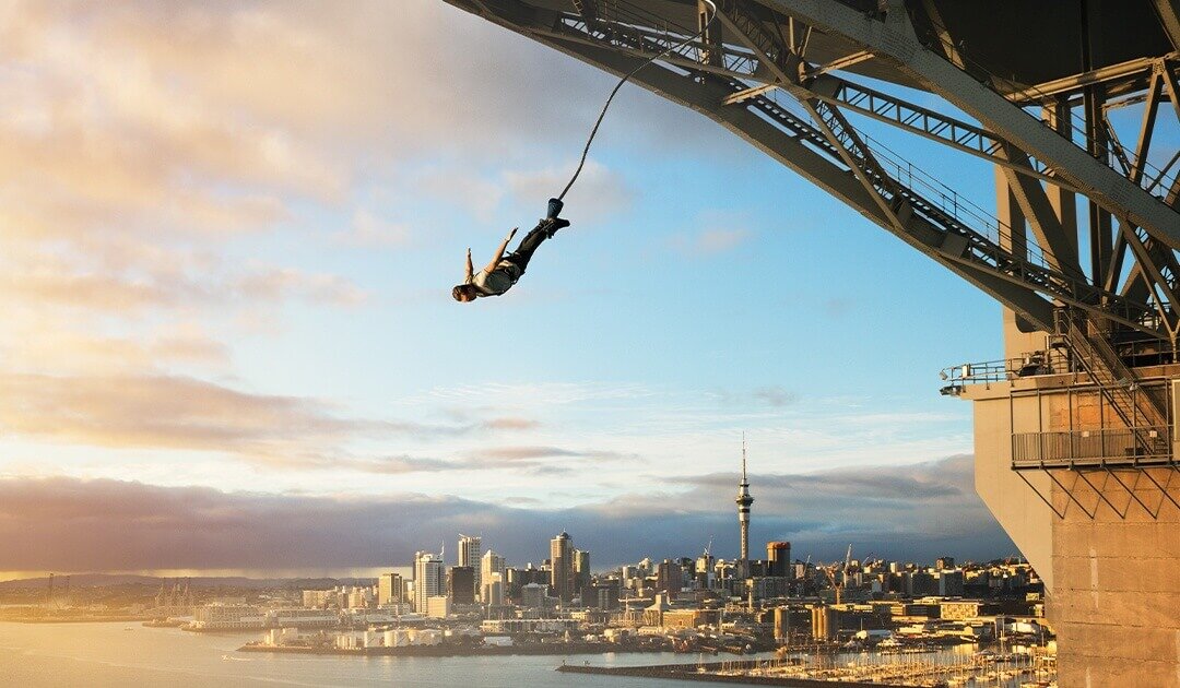 Customer testimonial backdrop showing AJ Hackett Bungy jump over Auckland Harbour — representing bold, unforgettable experiences tied to the Kelray lifestyle